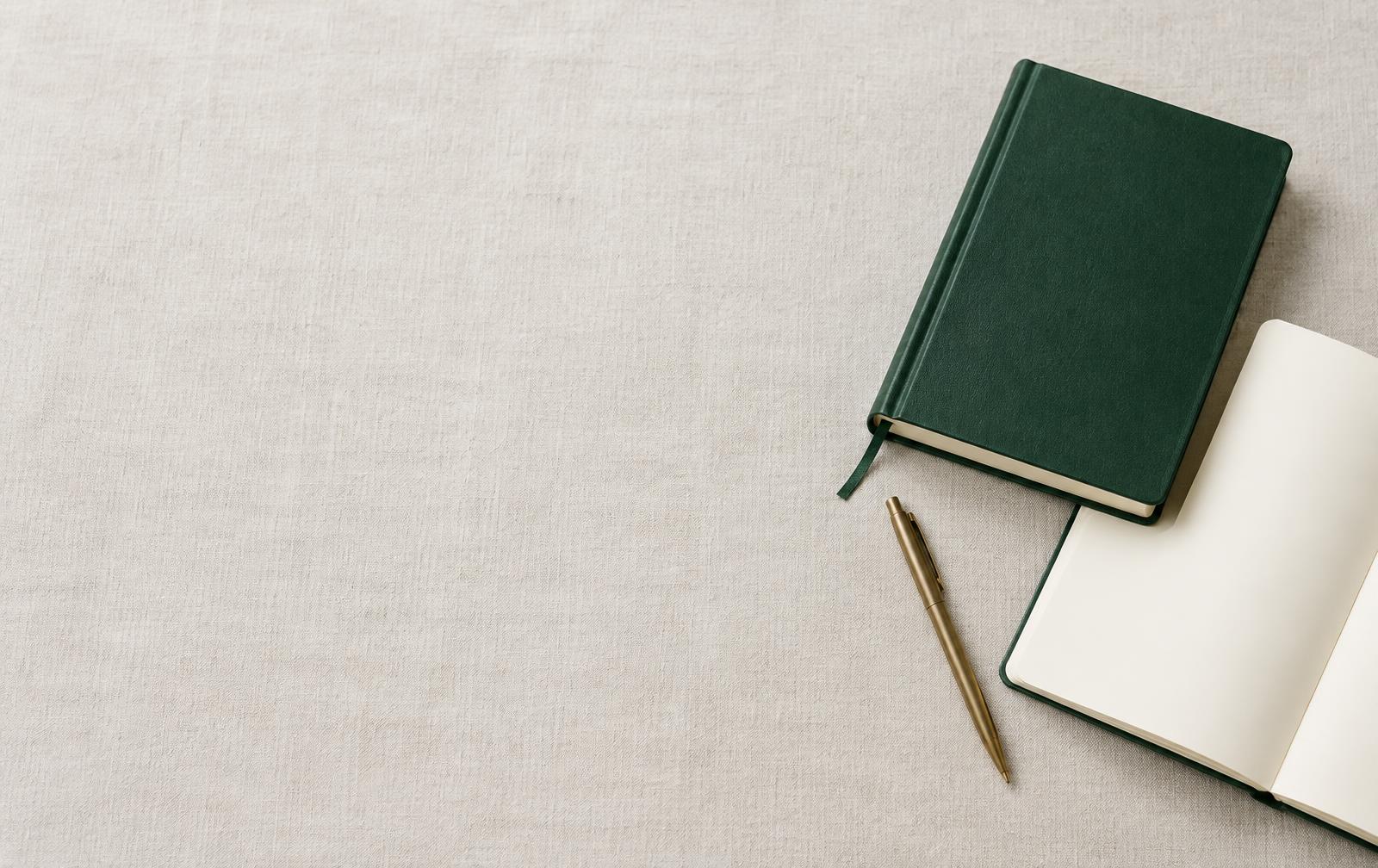 A Bible, open journal and brass pen on an ivory writing surface